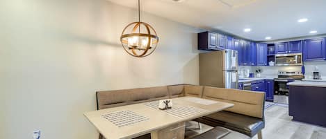 A modern kitchen with dark blue cabinets, stainless steel appliances, and a central island.