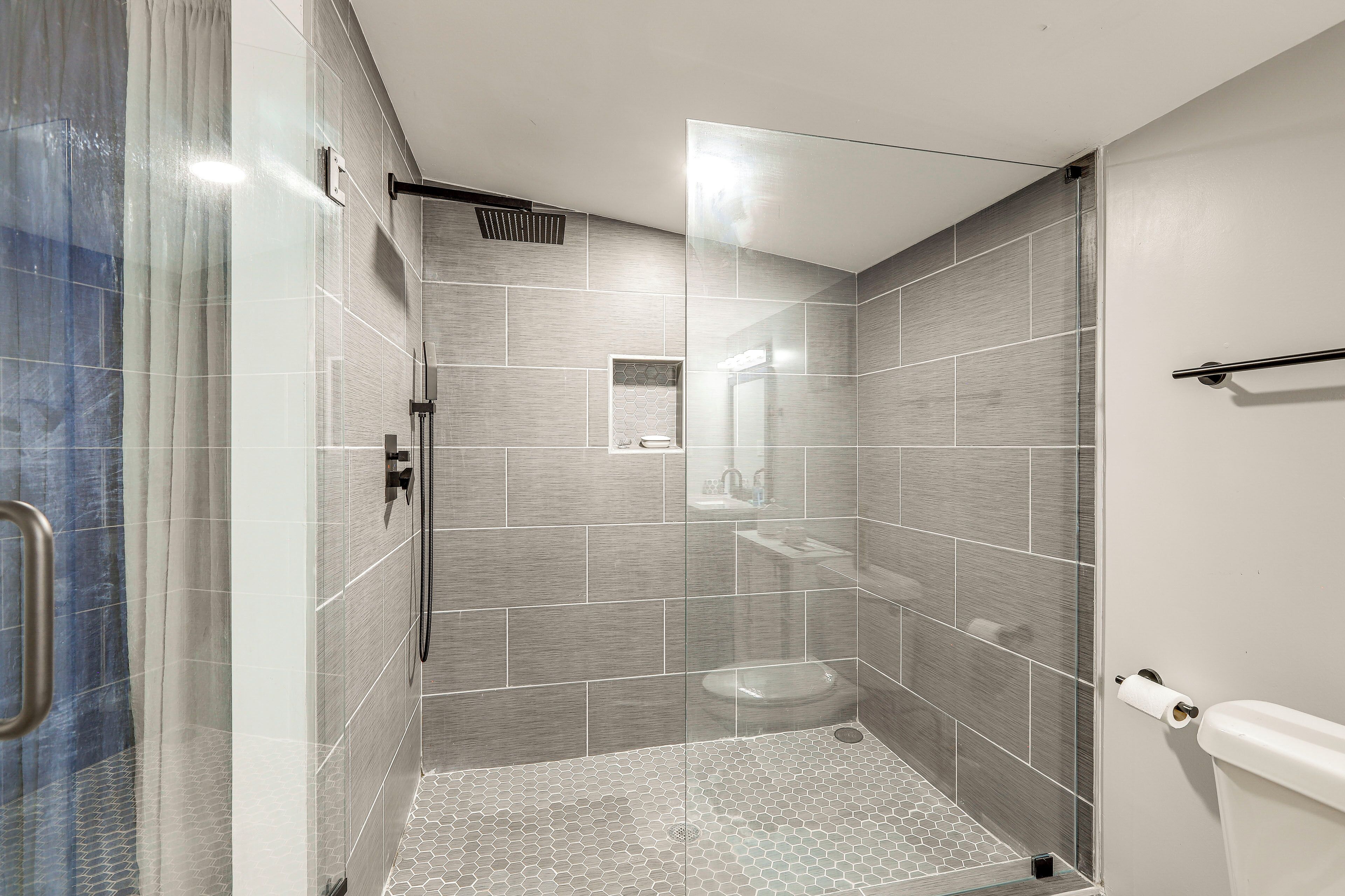 A modern bathroom with a glass shower enclosure, a toilet, and a sink.