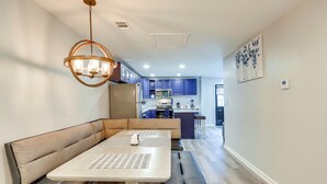 A modern kitchen with blue cabinets, a central island, and a dining area with a bench and table. - Conyers Vacation Rental w/ Pool: 5 Mi to Olde Town (Conyers)