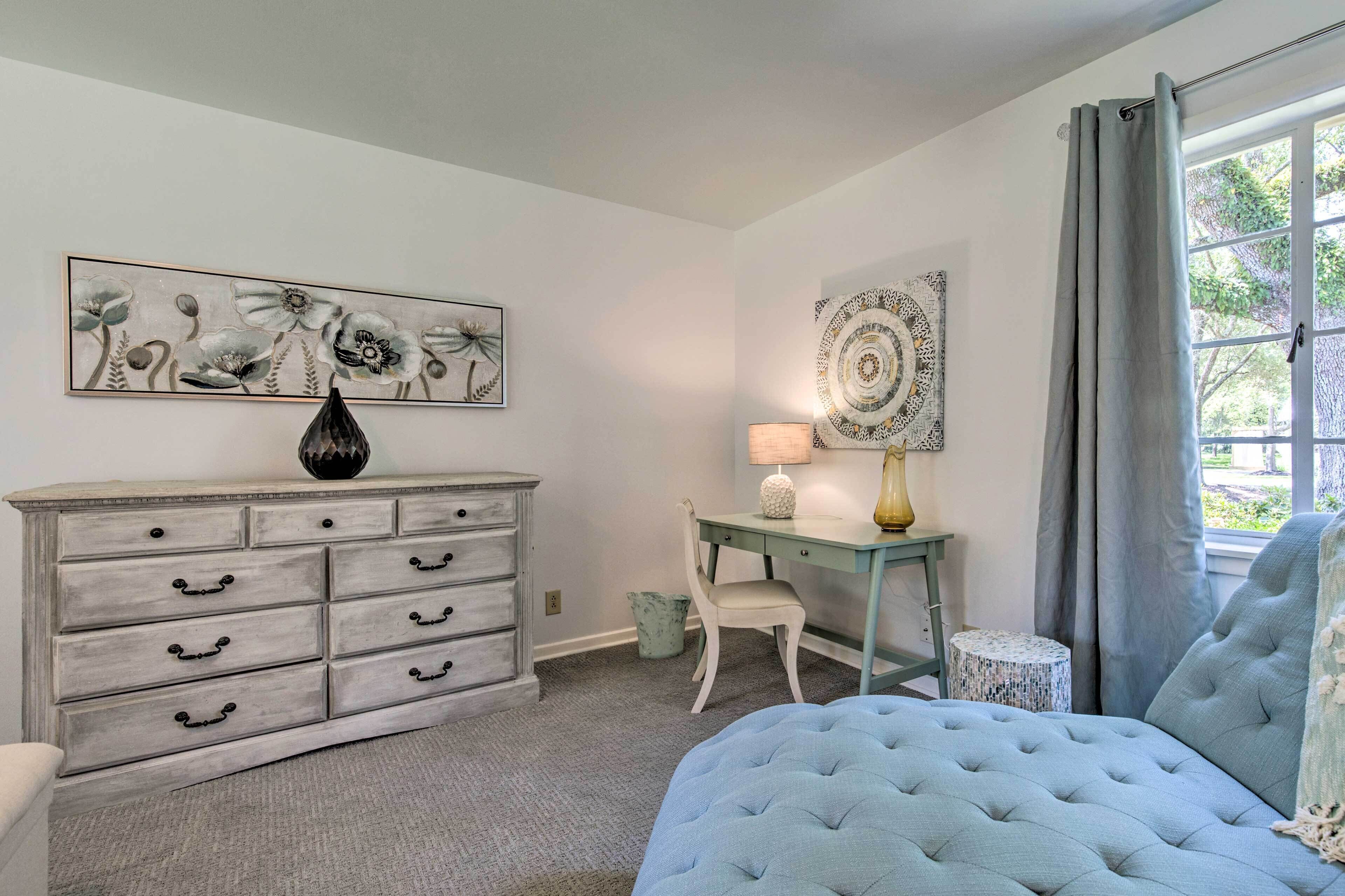 Un dormitorio con cama, cómoda, escritorio y dos lámparas fijadas a la pared.