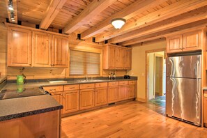 A kitchen with wooden cabinets, a stainless steel refrigerator, granite countertops, and a wooden ceiling. - Peaceful Tignall Cabin on Strom Thurmond Lake! (Tignall)