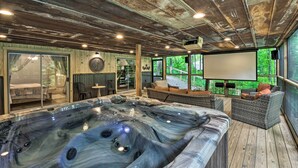 Ein Whirlpool in einer Holzblockhütte mit großem Fenster und Projektionsleinwand.