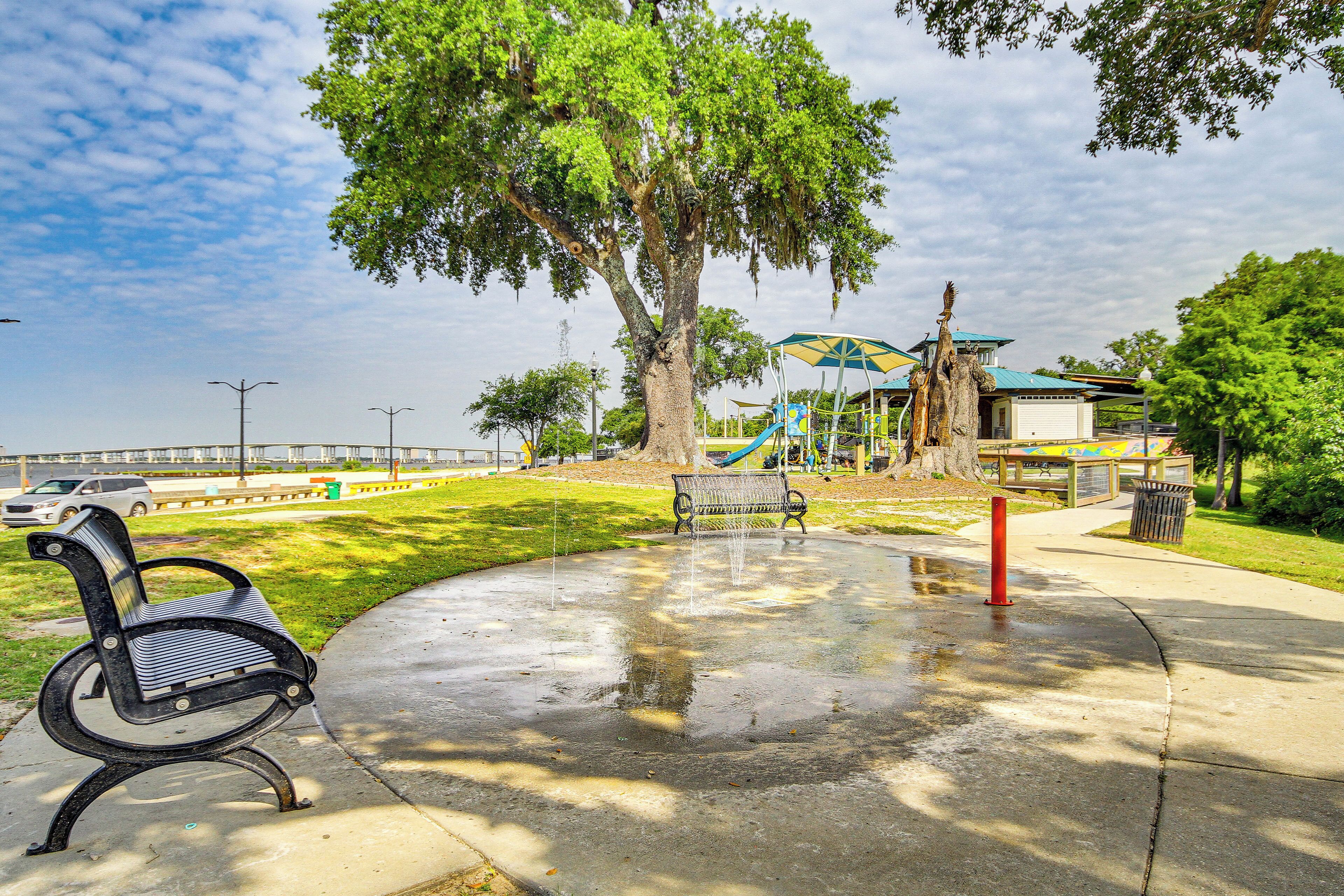 A park with a bench, a playground, and a tree.