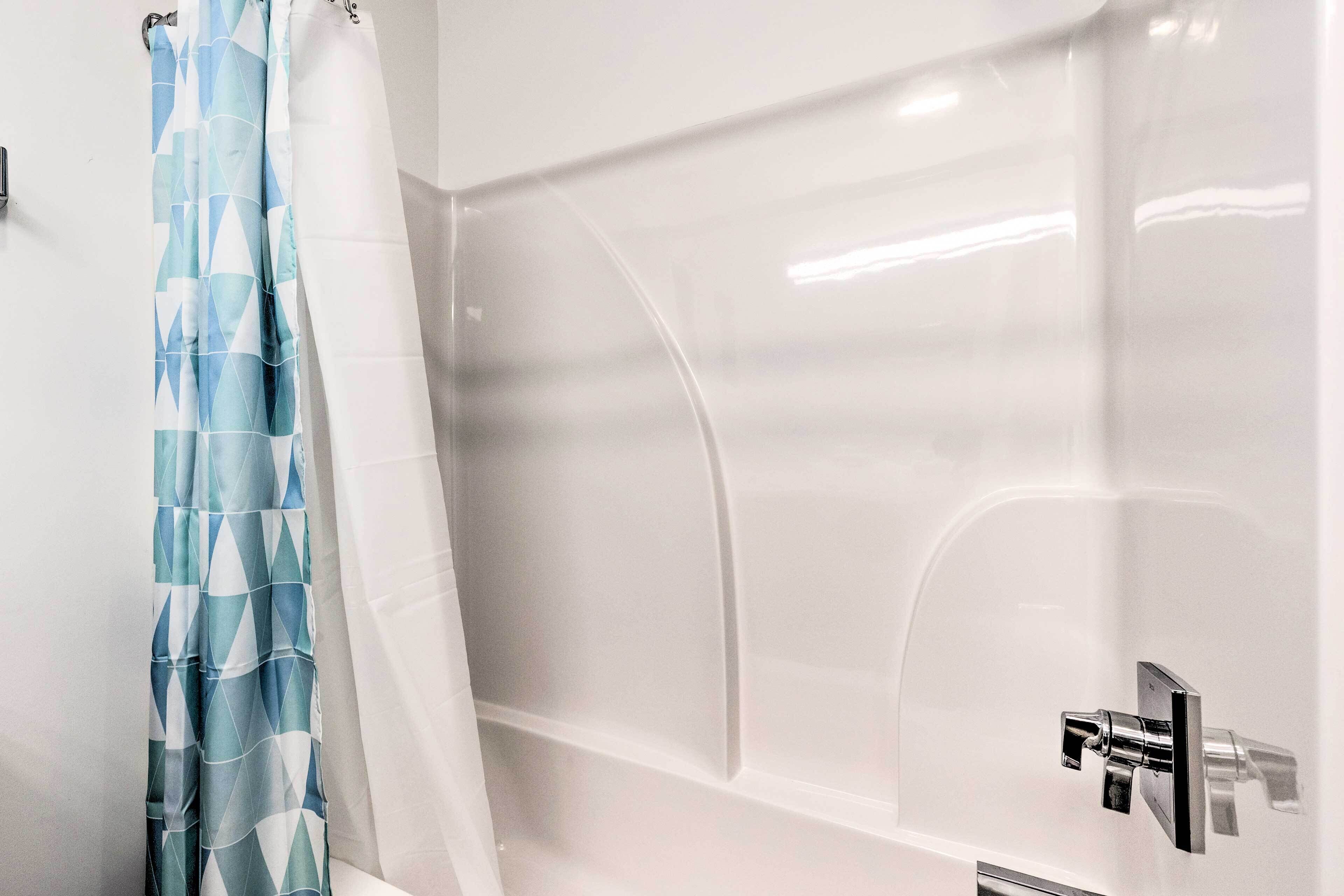 A modern bathroom with a bathtub, a shower curtain, and a faucet.