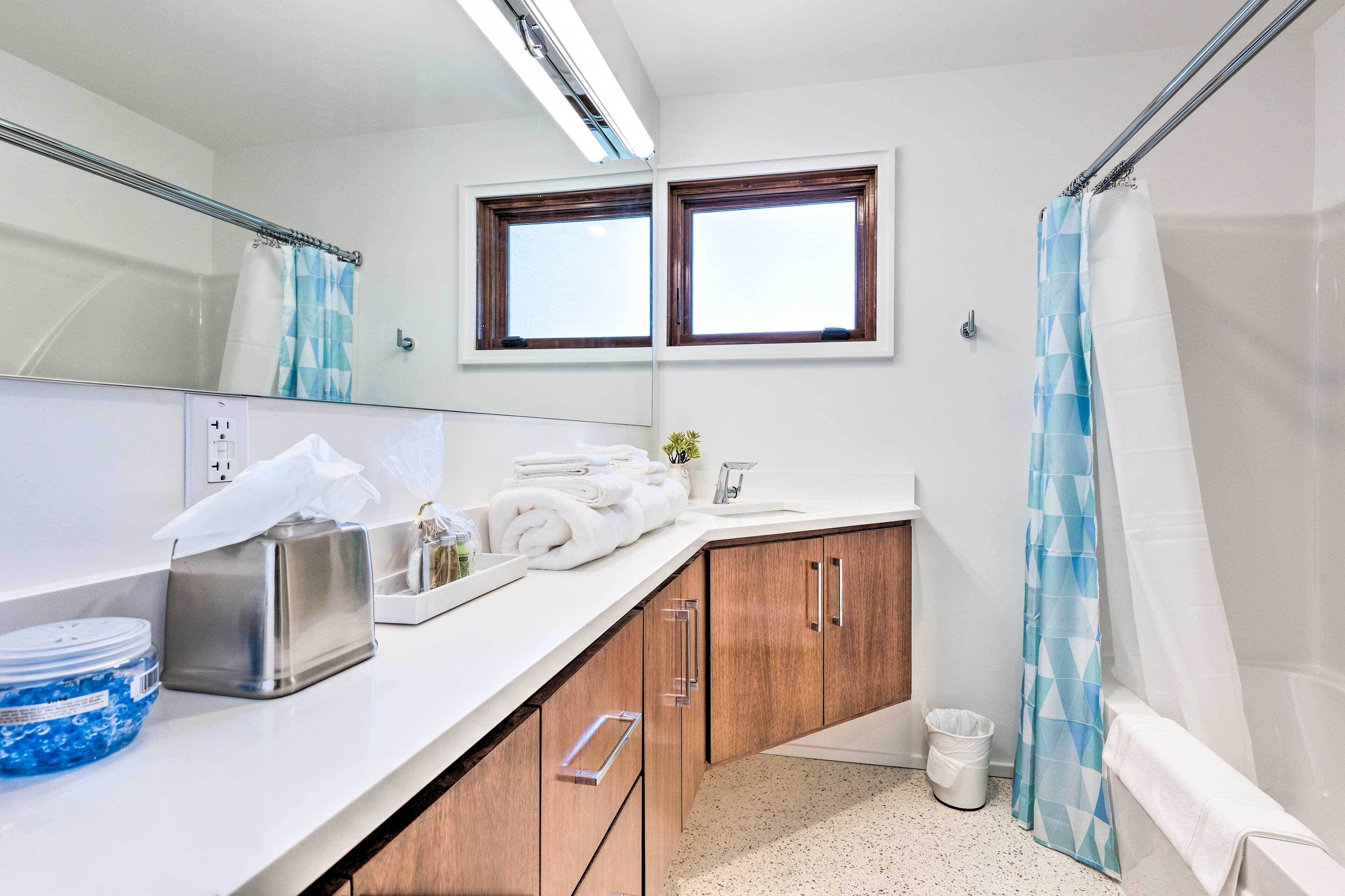 Ein Badezimmer mit Dusche, Waschbecken, Spiegel und Fenster.