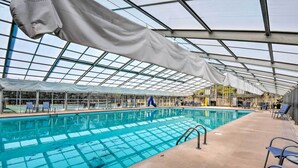 An indoor swimming pool with clear glass ceilings, blue water, and lounge chairs along the sides. - Ellijay Escape: Hike, Shop, Explore & More! (Ellijay)