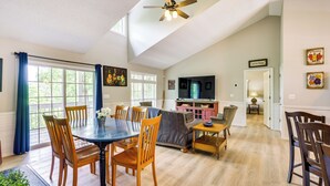 A spacious living room with a dining area, a ceiling fan, a television, and a door leading to another room. - Ellijay Escape: Hike, Shop, Explore & More! (Ellijay)