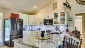 A kitchen with white cabinets, a stainless steel refrigerator, a microwave, and a wooden dining table with chairs. - Ellijay Escape: Hike, Shop, Explore & More! (Ellijay)