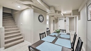 A dining area with a long table, chairs, and a clock on the wall.