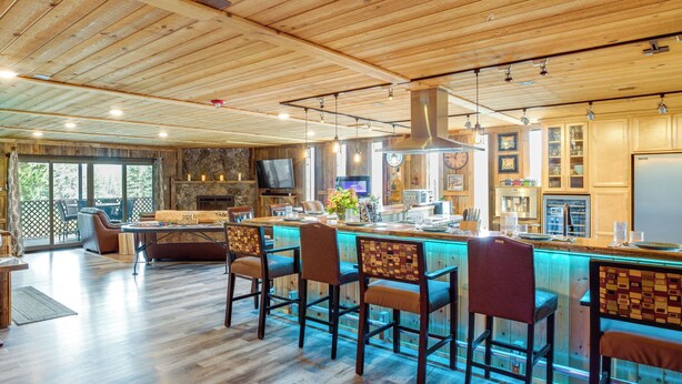 A spacious kitchen with wooden flooring, a bar area with bar stools, a stone fireplace, and a large TV mounted on the wall. - Game Room, Mtn Views! Unit 1 Mi to Heavenly Resort (Stateline)
