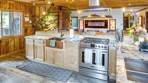 A kitchen with wooden cabinets, a granite countertop, stainless steel appliances, and a stone wall. - Game Room, Mtn Views! Unit 1 Mi to Heavenly Resort (Stateline)
