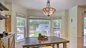 A kitchen with a wooden table, a stained glass light fixture, and large windows. - Martinez Retreat w/ Seasonal Pool: 9 Mi to Masters (Grovetown)