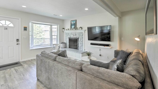 A modern living room with a sectional sofa, a fireplace, a flat-screen TV, and a large window. - < 1 Mi to Slopes! 'heavenly Daze Chalet' in Tahoe (Stateline)