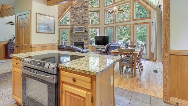 A spacious kitchen with granite countertops, a built-in oven, and a stone fireplace. - Murrayville Lakefront Cabin w/ Boat Slip & Grill! (Murrayville)