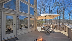 A deck with outdoor furniture, a fire pit, and a large umbrella. - Murrayville Lakefront Cabin w/ Boat Slip & Grill! (Murrayville)