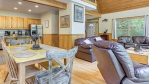 A spacious living area with a dining table, leather sofa, and a kitchen in the background. - Murrayville Lakefront Cabin w/ Boat Slip & Grill! (Murrayville)