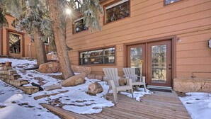 Eine Holzterrasse mit Adirondack-Stühlen, einer Steinbank und verschneitem Grund.