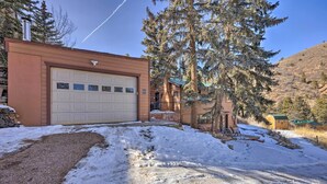 Ein Wohnhaus mit Garage, Auffahrt und einem großen immergrünen Baum.