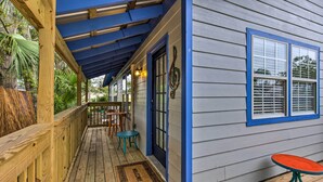 A wooden deck with a blue ceiling, a door with a treble clef decoration, and a window with a blue frame.