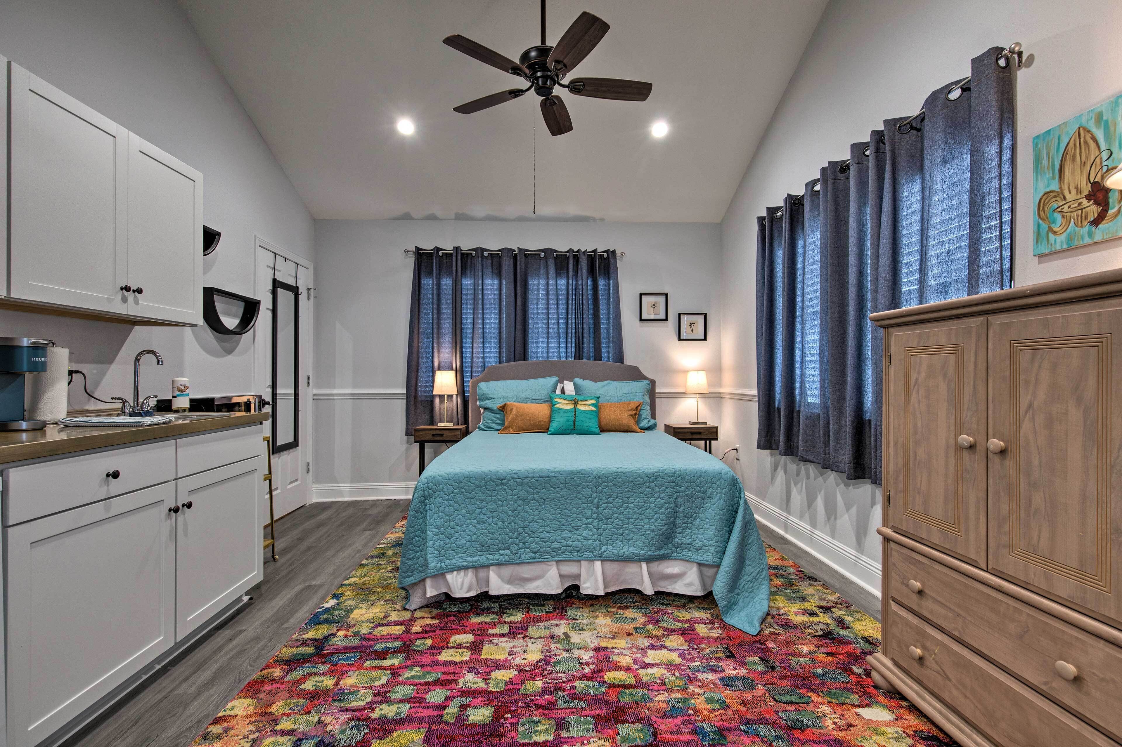 A bedroom with a bed, a ceiling fan, a window with curtains, a nightstand, and a dresser.