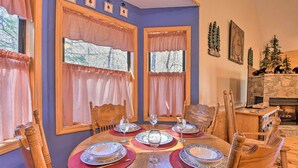 A dining room with a wooden table set for six, surrounded by wooden chairs.