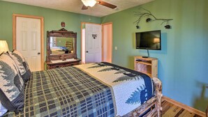 A bedroom with a bed, a ceiling fan, a television, and a dresser.