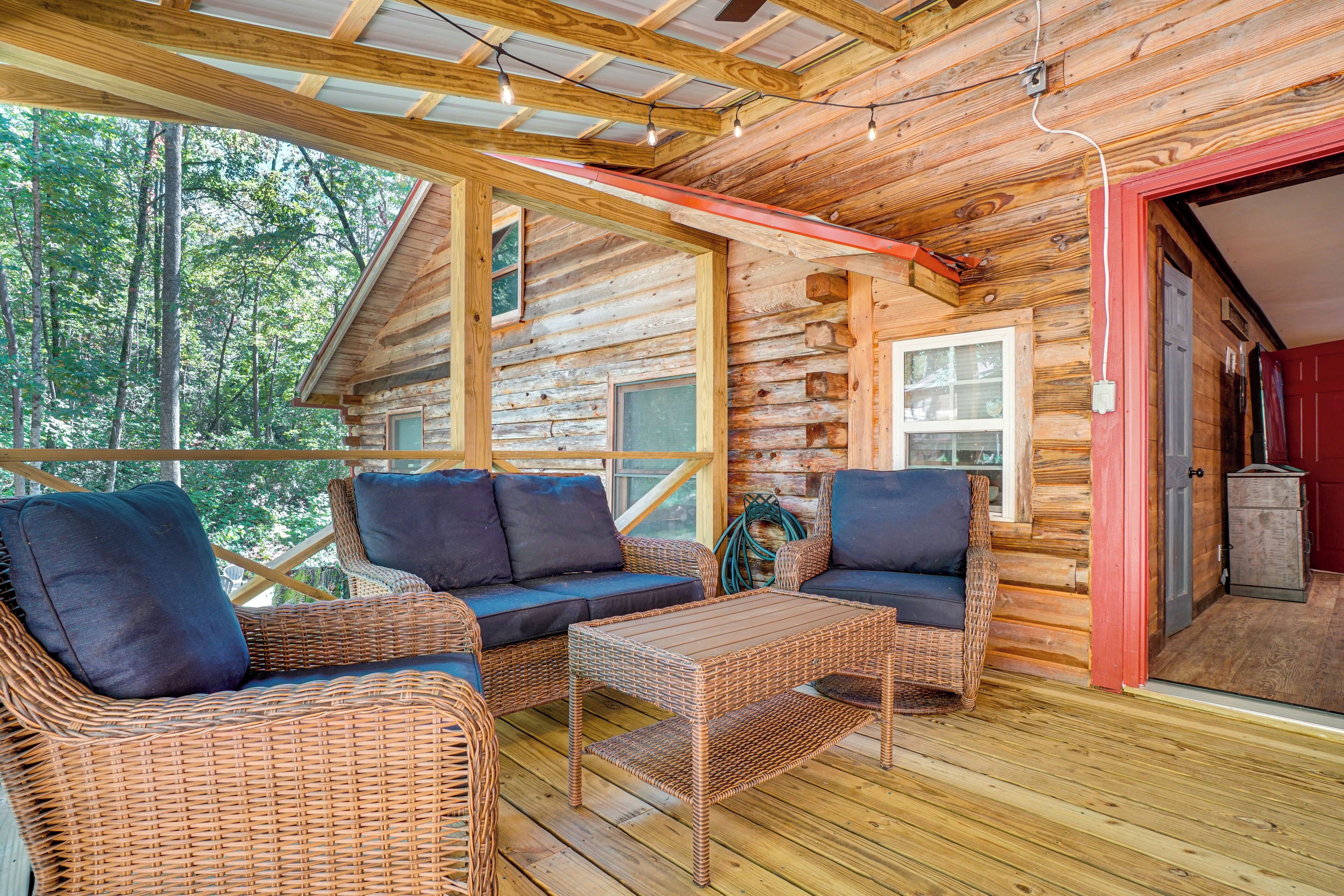 Een vakantiehuis van hout met rieten meubels, een houten terras en uitzicht op het bos.