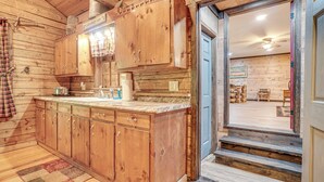 A wooden cabin interior with a kitchen area featuring wooden cabinets and a marble countertop.