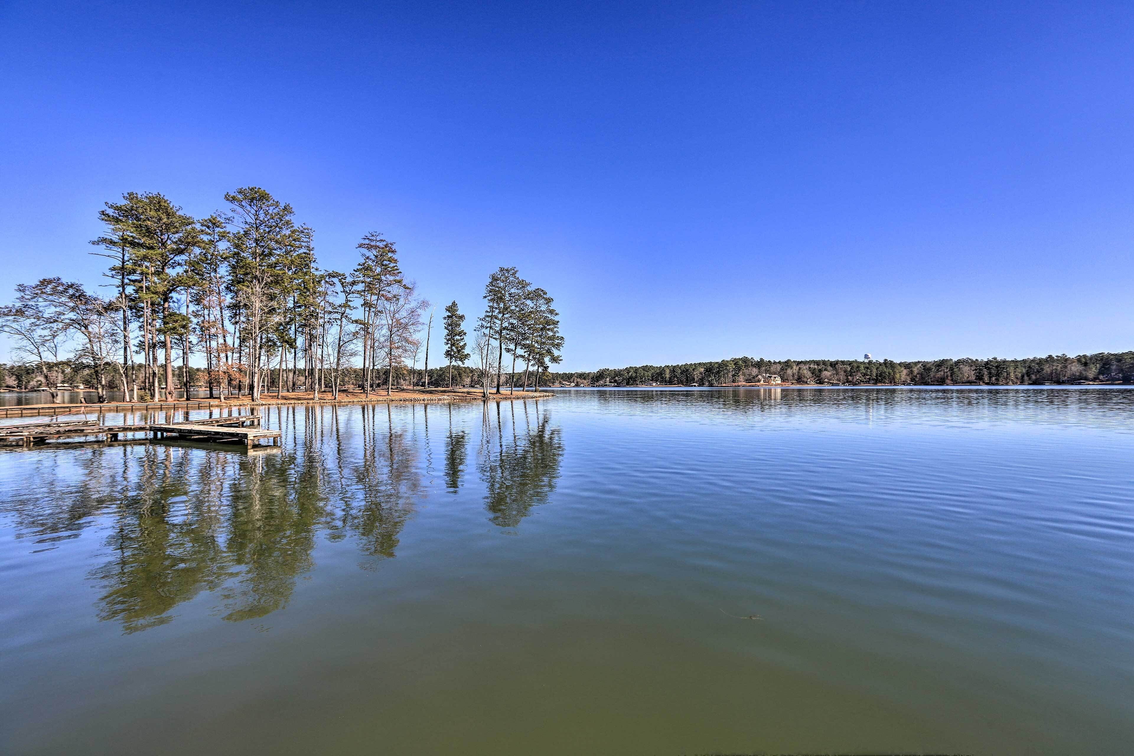 A calm lake with a dock and trees reflecting on the water.