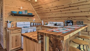 Un interior de madera con una zona de cocina que incluye una barra larga, taburetes y un letrero de estación de café.