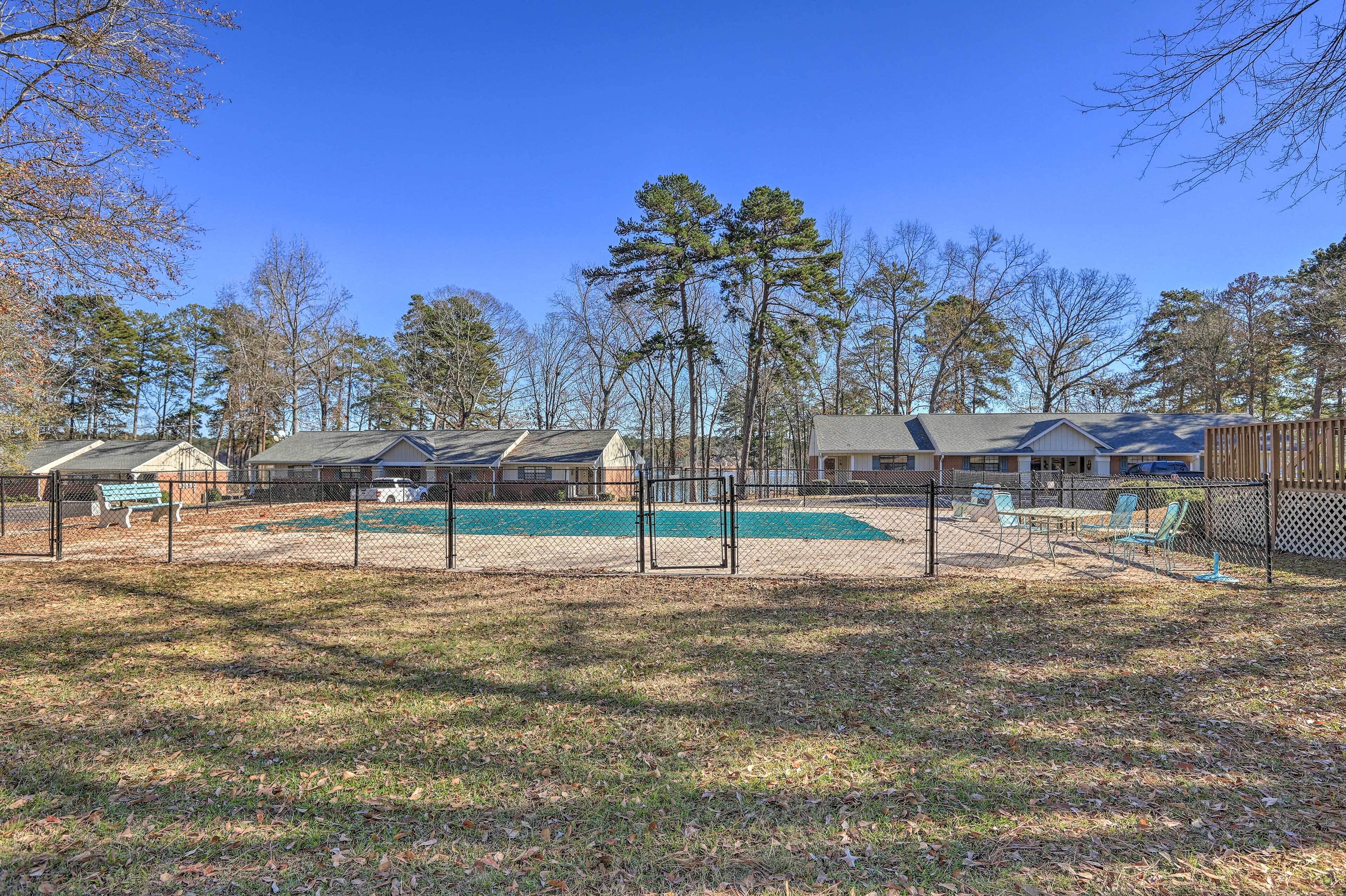 A fenced outdoor area with a pool, benches, and a playground.