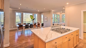 A spacious kitchen with a large island, wooden cabinets, and a dining area with chairs and a table. - Luxe Big Canoe Resort Home w/ 3 Decks & Mtn Views! (Dawsonville)
