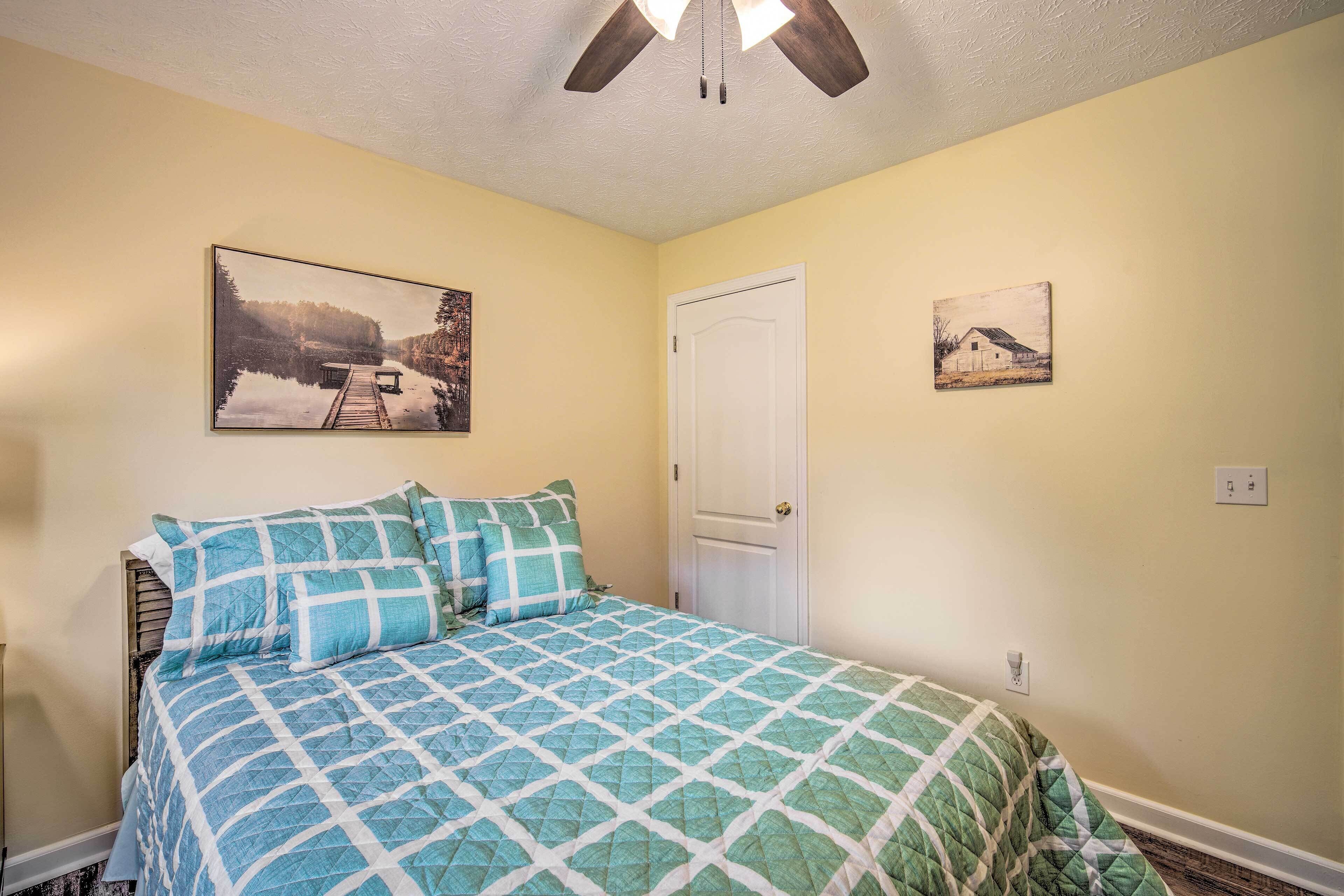A bedroom with a bed, a door, and two wall-mounted pictures.