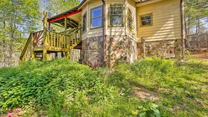 A house with a stone foundation and a wooden deck. - Charming Cottage w/ Deck in Blue Ridge! (Blue Ridge)