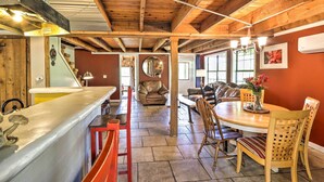 A spacious living area with a wooden ceiling, a dining table with chairs, a sofa, and a fireplace. - Charming Cottage w/ Deck in Blue Ridge! (Blue Ridge)