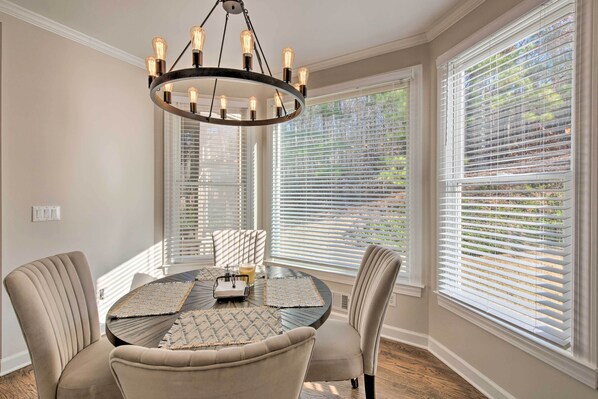 A dining area with a round table, beige chairs, and a chandelier. - Updated Mableton Home ~ 14 Miles to Downtown Atl! (Mableton)