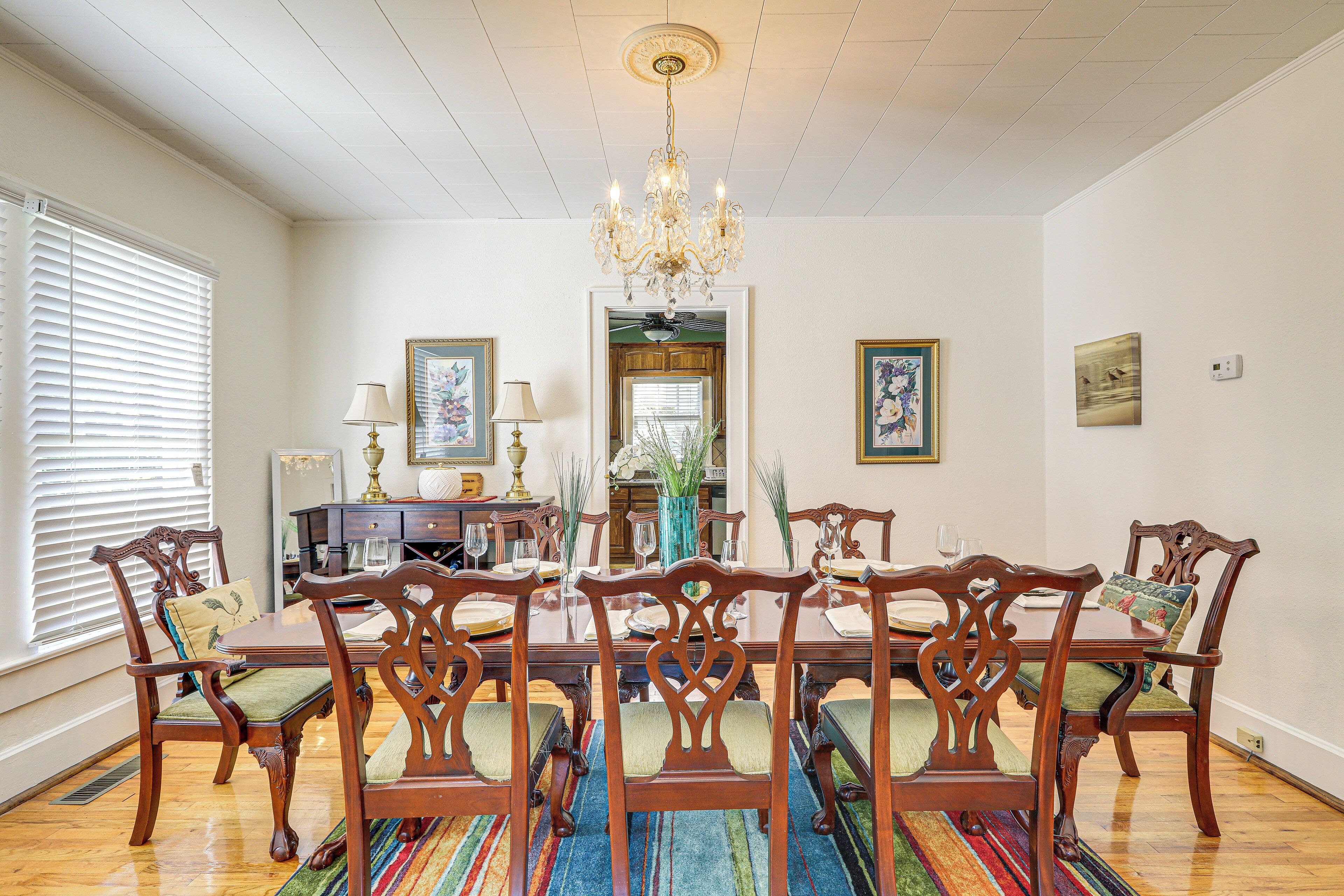 A dining room with a wooden table and chairs, a chandelier, and artwork on the walls.