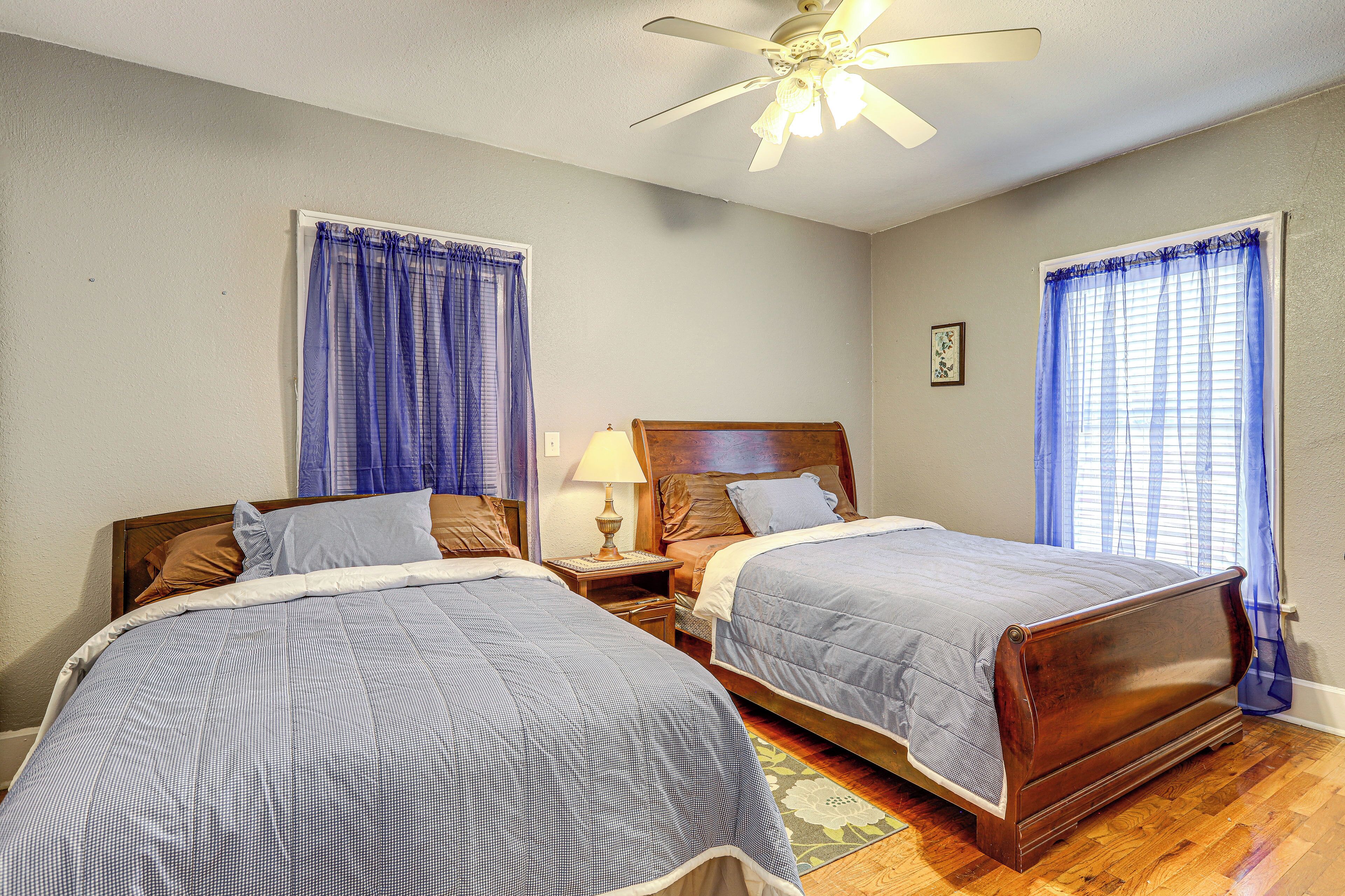 A bedroom with two beds, a ceiling fan, and a nightstand with a lamp.