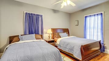 A bedroom with two beds, a ceiling fan, and a nightstand with a lamp.