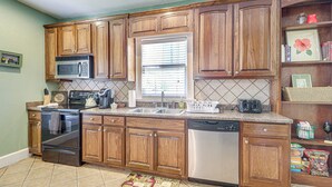A kitchen with wooden cabinets, a microwave, a dishwasher, and a window with blinds. - Main Street Home: 1 Mi to Callaway Gardens (Pine Mountain)