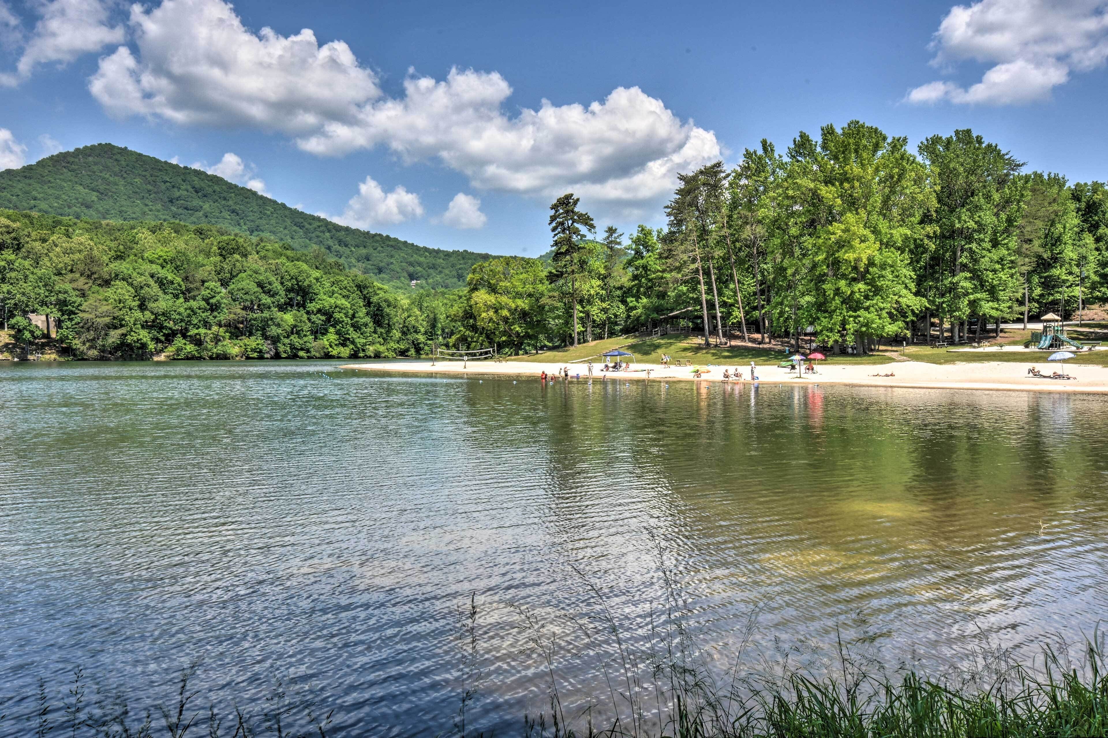 A lake with a forested hillside, a sandy beach, and a playground.