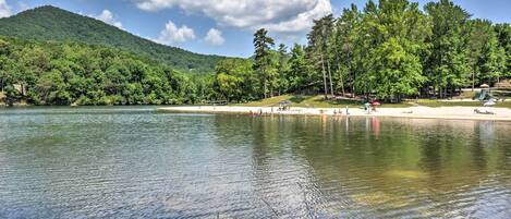 A lake with a forested hillside, a sandy beach, and a playground.