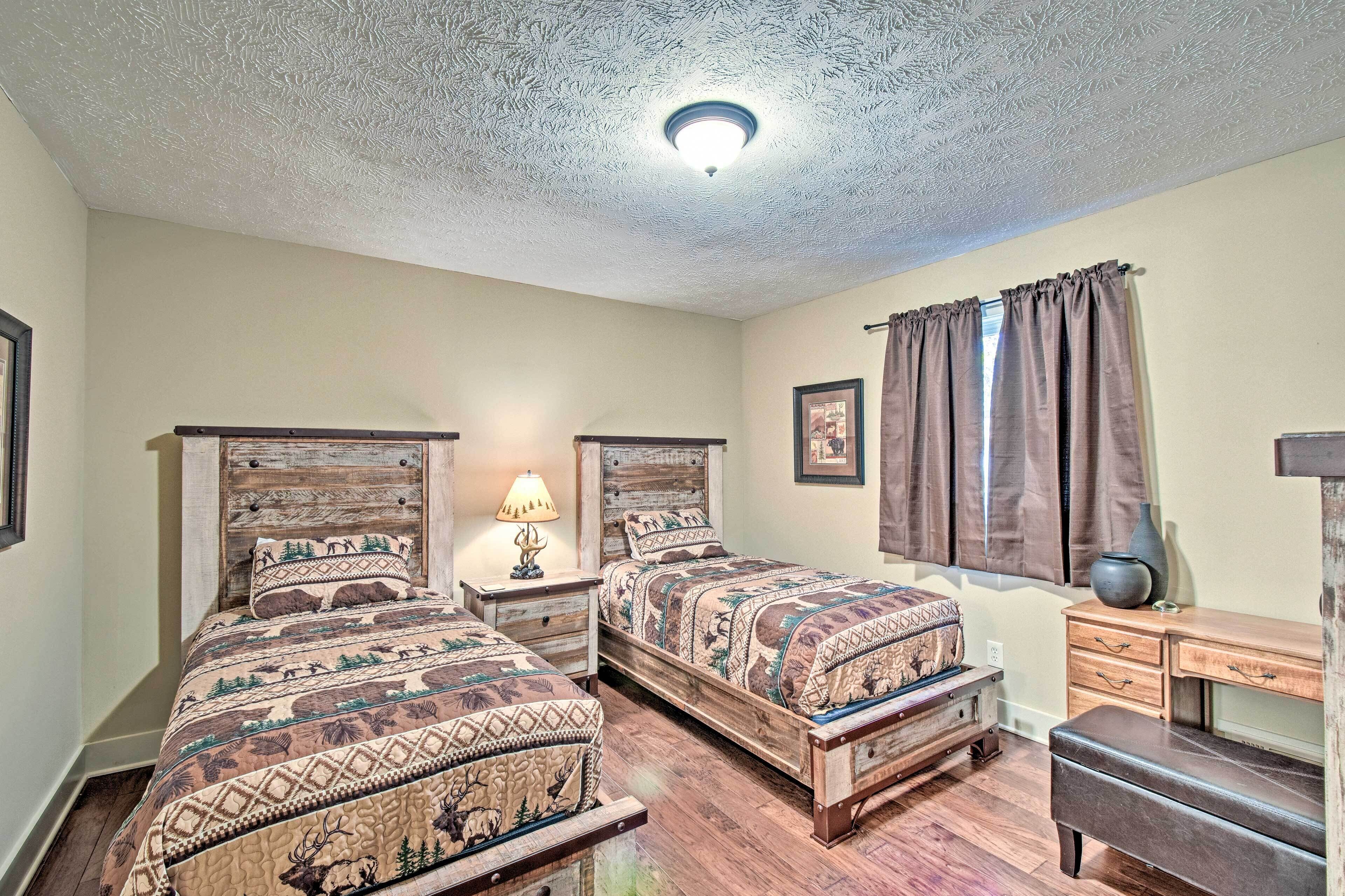 A bedroom with two wooden beds, a nightstand with a lamp, a dresser, and a window with curtains.