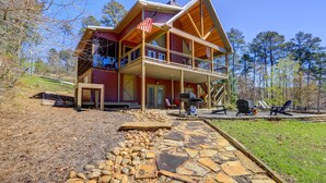 A two-story wooden cabin with a porch, stone pathway, and outdoor seating area. - Sparta Home w/ On-site Lake Access! (Milledgeville)