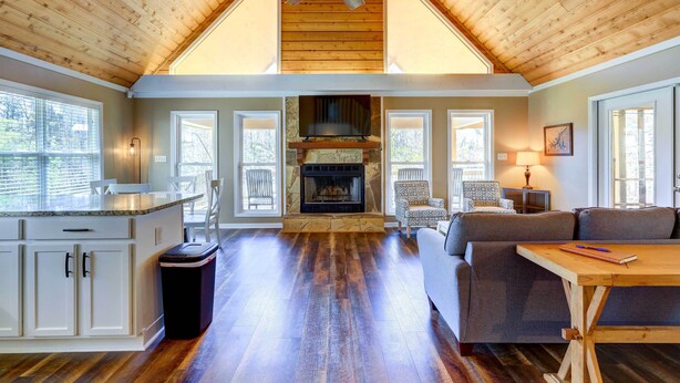 A spacious living area with a fireplace, wooden ceiling, and large windows. - Sparta Home w/ On-site Lake Access! (Milledgeville)