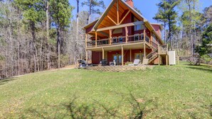 A two-story log cabin with a balcony, surrounded by a forest. - Sparta Home w/ On-site Lake Access! (Milledgeville)