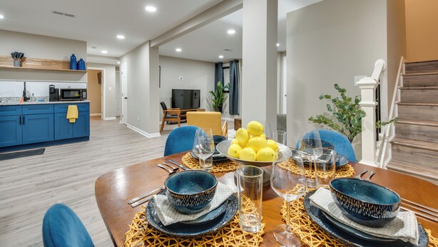 Un coin repas moderne avec une table en bois dressée pour quatre personnes, entourée de chaises bleues. Un saladier rempli de citrons et des verres sont posés sur la table.