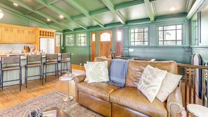 A spacious living area with a brown leather couch, wooden chairs, and a kitchen in the background. - Waterfront Escape on Blue Ridge Lake w/ Dock! (Morganton)