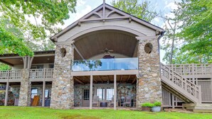 A two-story stone building with a covered patio, outdoor seating, and a staircase. - Waterfront Escape on Blue Ridge Lake w/ Dock! (Morganton)