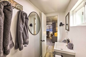 Een badkamer met een wit wastafel, een spiegel en handdoeken aan een rek.